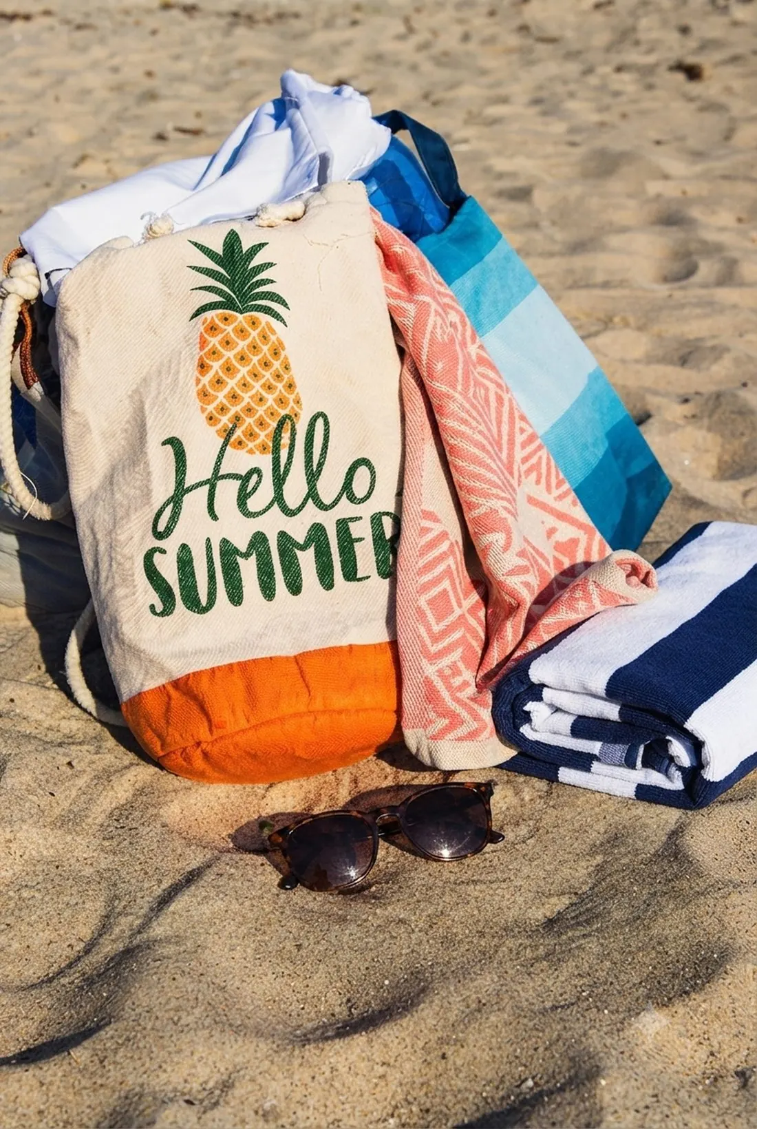A beach bag, towels, and sunglasses packed and ready on the sand